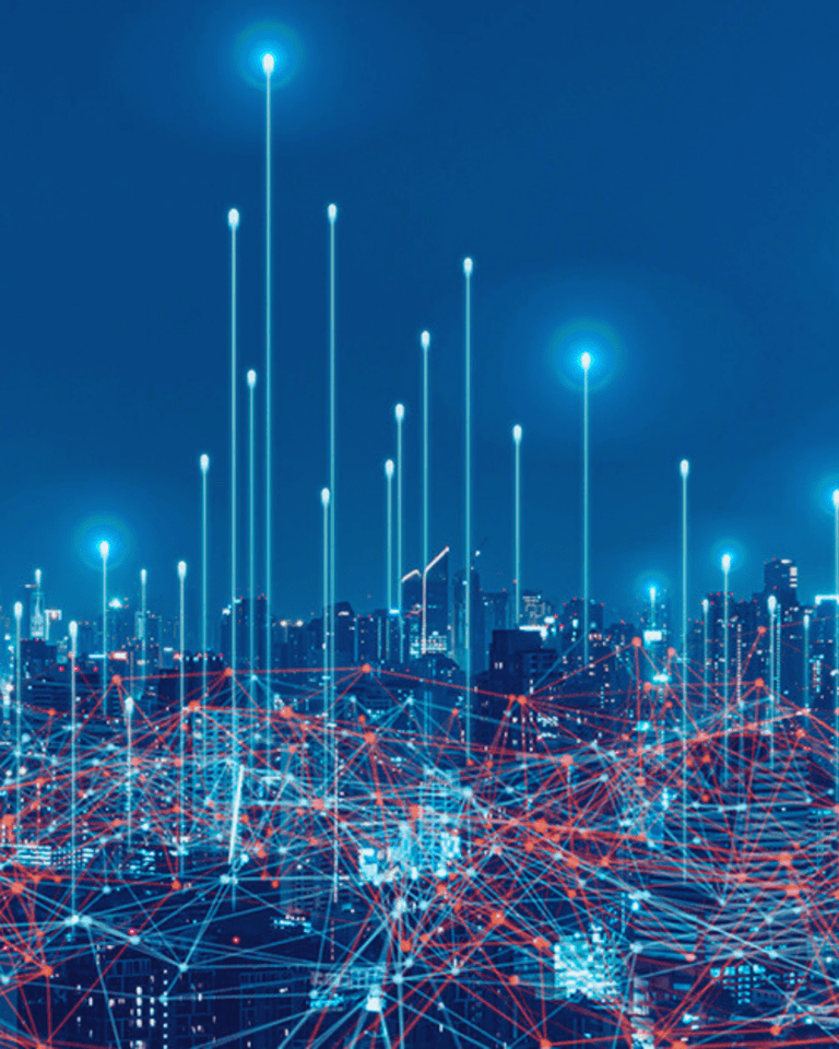 Trustack MSP Cyber Security, IT Services, IT Support. A cityscape at night is depicted with tall buildings illuminated by blue lights. Digital lines and nodes connect various points above the city, suggesting a network or digital communication system, hinting at the intricate web of cybersecurity in our evolving threat landscape. The background sky is dark blue.