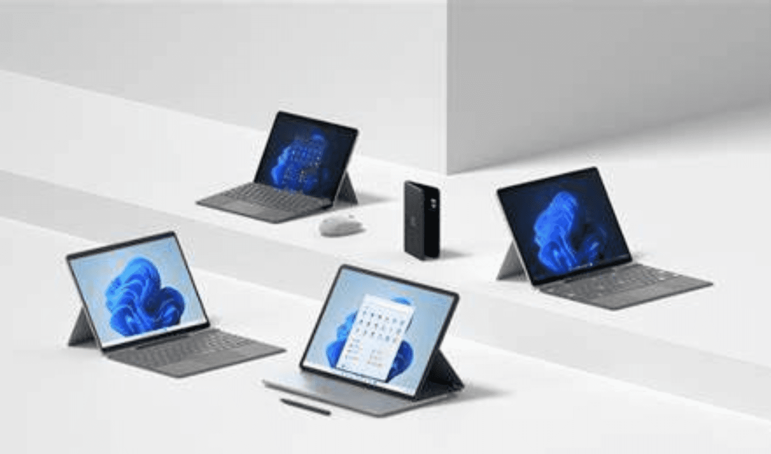 Trustack MSP Cyber Security, IT Services, IT Support. The image shows four gray tablets with detachable keyboards standing on white platforms. The tablets display different screens, and a stylus, a mouse, and a black rectangular object are also visible. The setup emphasizes the critical need for robust disaster recovery in a minimalistic white background.