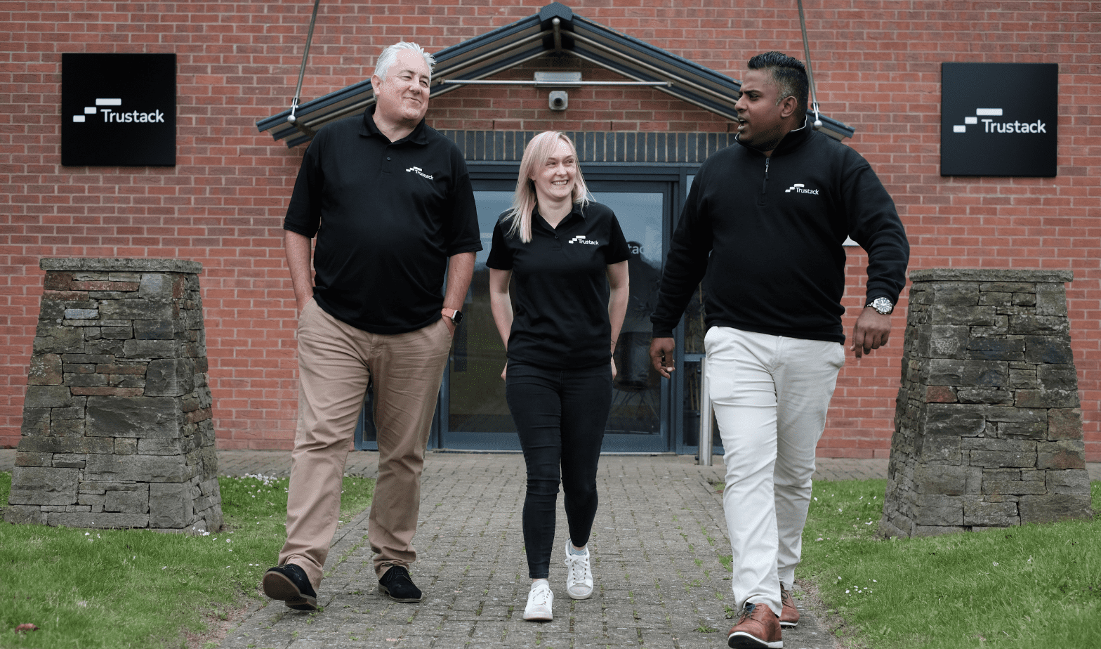 Image of three trustack employees walking outside infront of the Trustack building