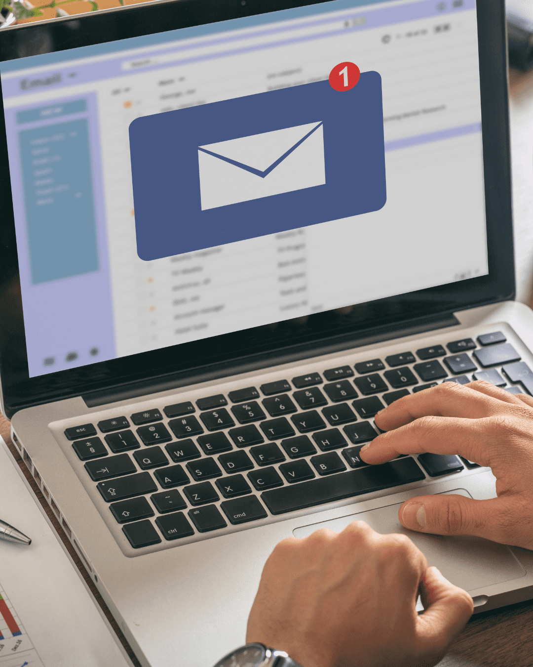 Trustack MSP Cyber Security, IT Services, IT Support. A person types on a laptop displaying an email application. A notification icon with a red circle and the number one appears, signaling a new email message. With phishing scams on the rise, recognizing suspicious emails is crucial. Documents and a pen are visible nearby. email scam image
