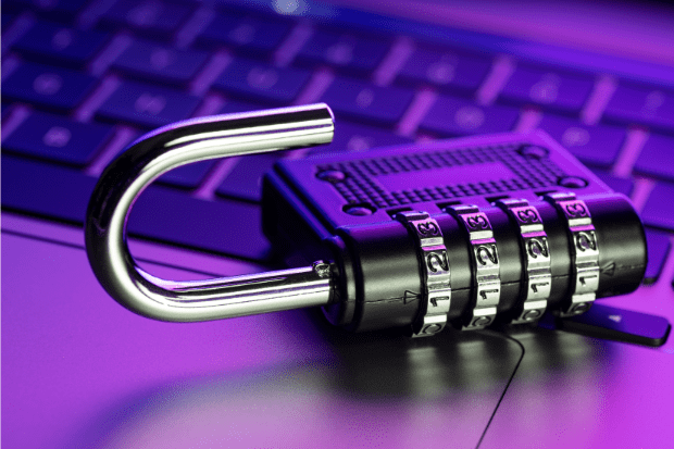 Trustack MSP Cyber Security, IT Services, IT Support. A combination padlock with its shackle open rests on a laptop keyboard, illuminated by purple and blue light—symbolising the importance of Azure CVE remediation in securing digital environments.