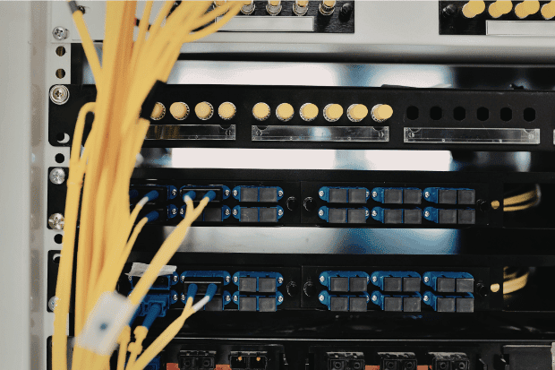 Trustack MSP Cyber Security, IT Services, IT Support. Close-up view of a network server rack with yellow fibre optic cables and multiple patch panels, highlighting virtualisation-ready infrastructure with hypervisor support for efficient data management.